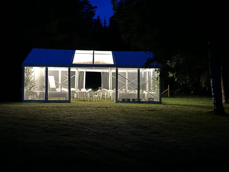 Party tent lit up at night against the forest