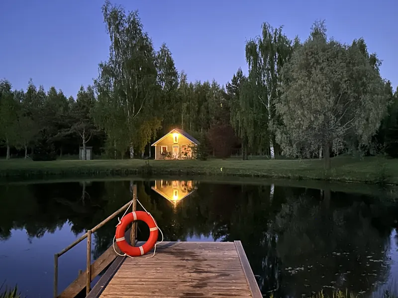 Sauna lit up at night, reflected in the pond